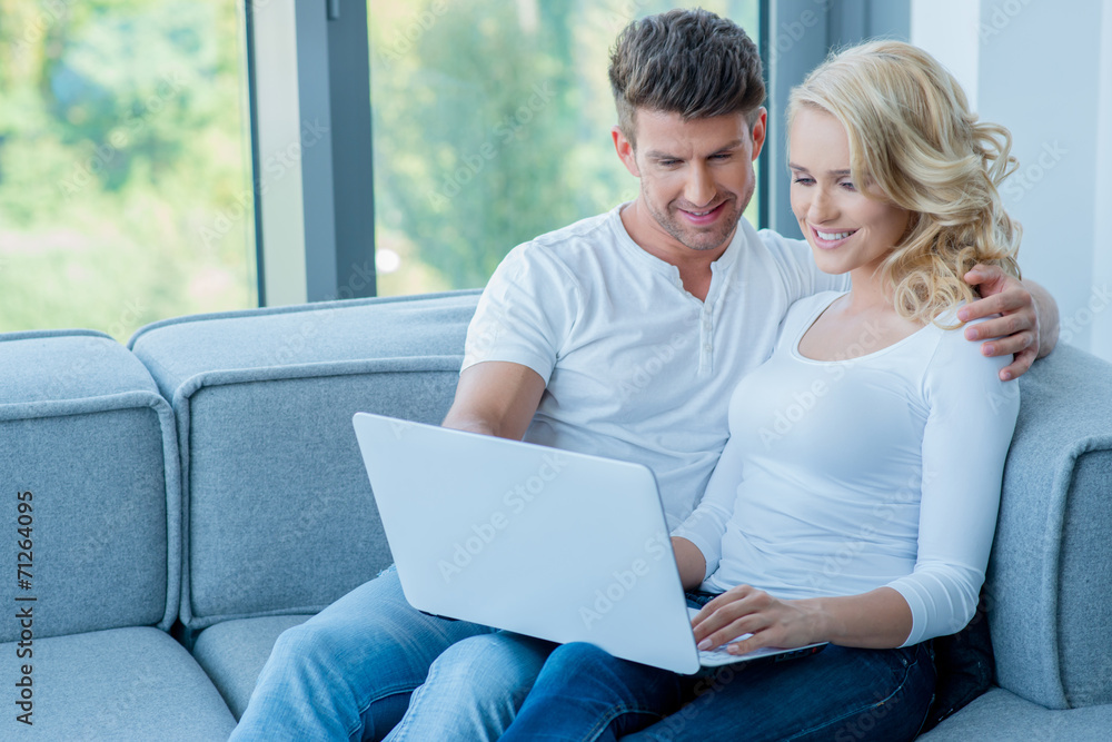 Young couple sitting sharing a laptop computer Young couple sitting sharing a laptop computer