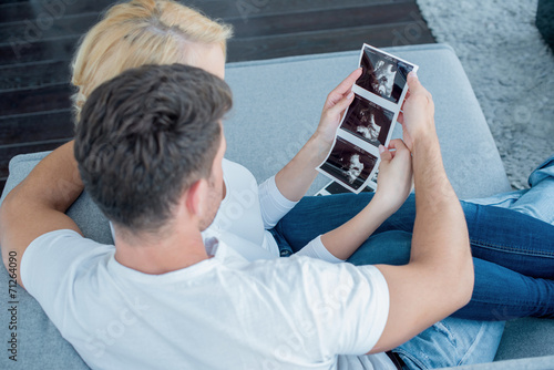 Sweet Couple on Couch Looking Ultrasound Photos