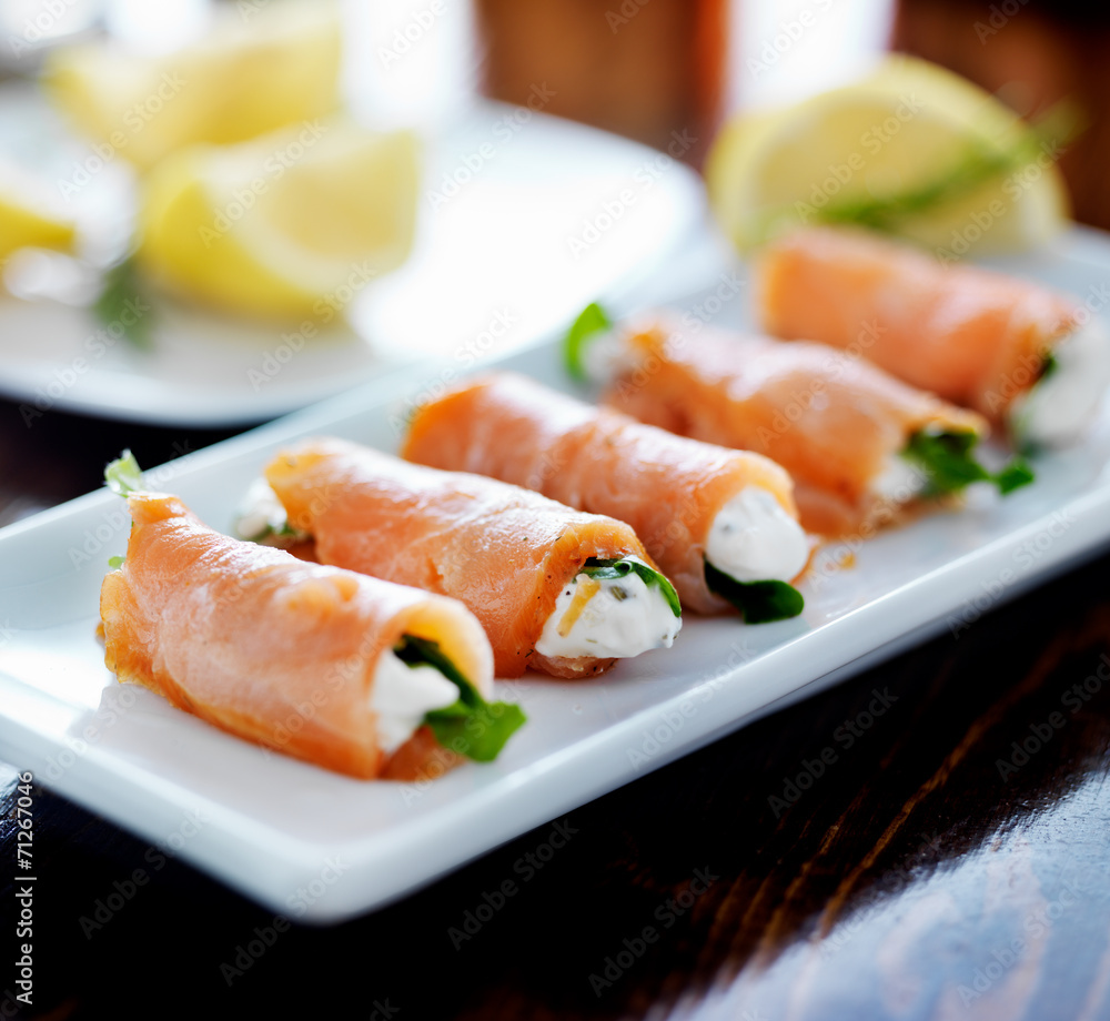 smoked salmon and arugul warp with cream cheese on platter smoked salmon and arugul warp with cream cheese on platter
