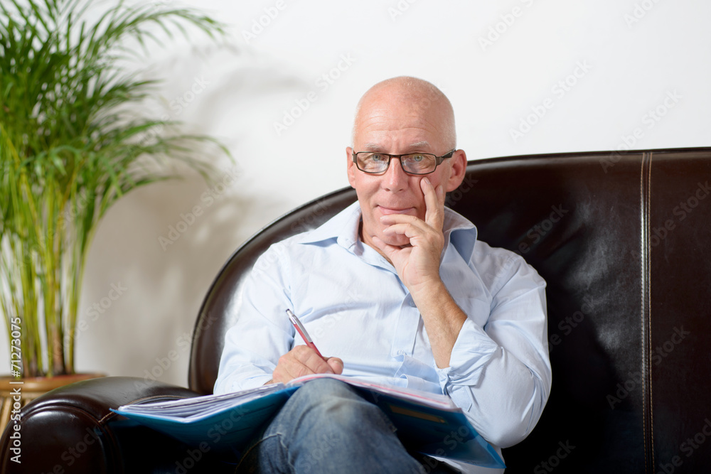 a senior man sitting in a sofa taking notes