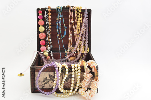 Necklace, pearls and jewellery into a wooden chest isolated on white