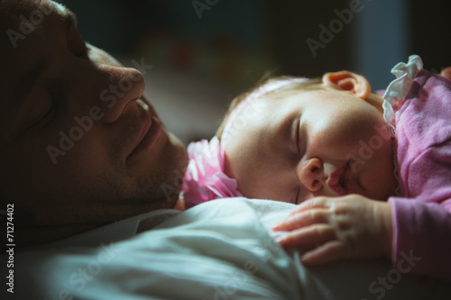 Image of young dad with cute little daughter in his arms