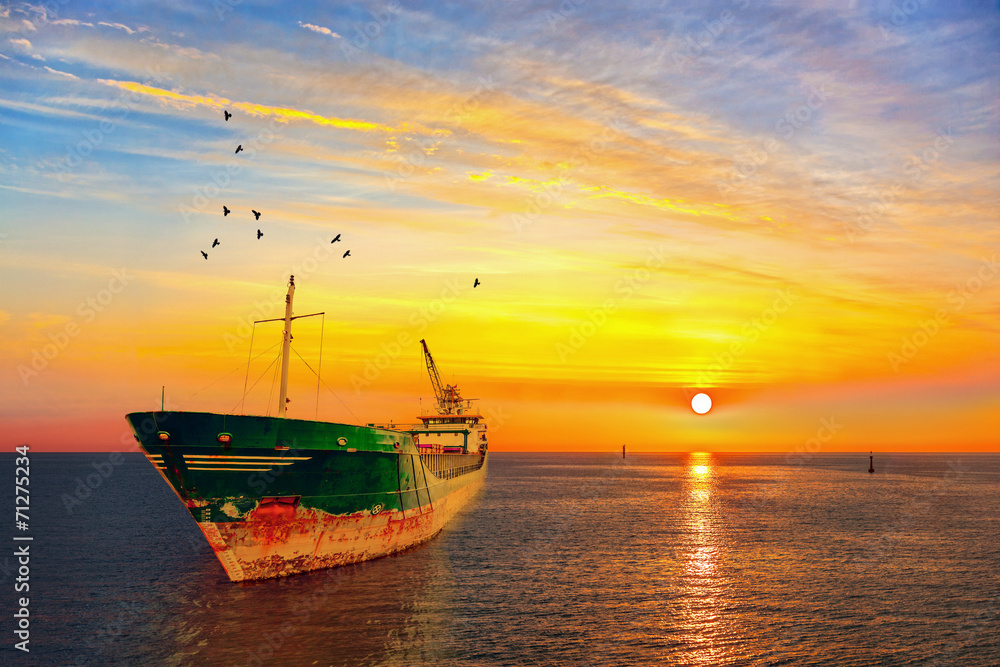 Beautiful sunrise with a dry cargo ship at sea.