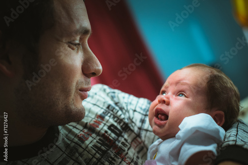 Image of young dad with cute little daughter in his arms