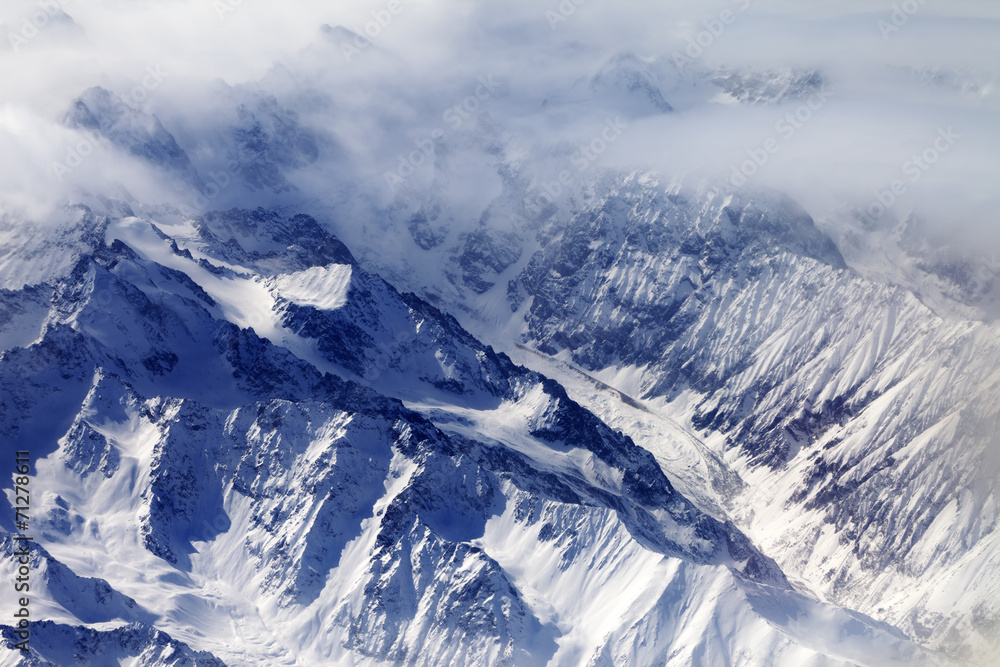 Top view on snow mountains and glacier in mist