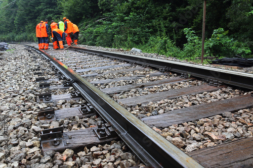 Workers in orange  raincoats repair railroad on rainy day