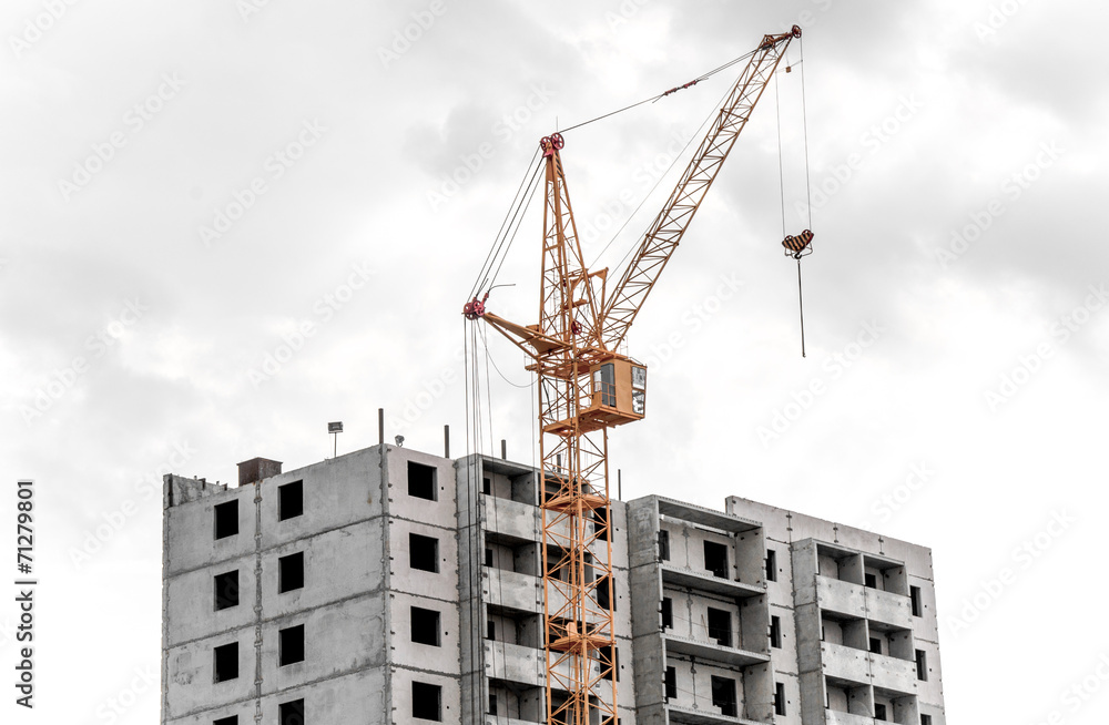A big yellow crane constructing a new high rise A big yellow crane constructing a new high rise