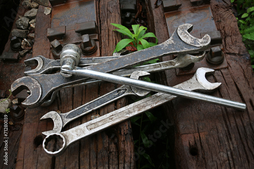 Worker tightens the screw on railroad with two spanners in hands