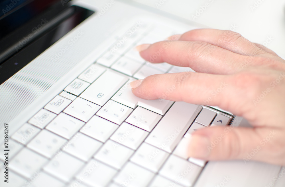 Female hand typing on a white keyboard Female hand typing on a white keyboard