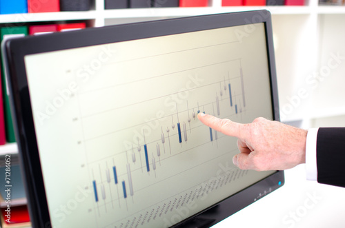 Index finger showing a screen with stock exchange data graph