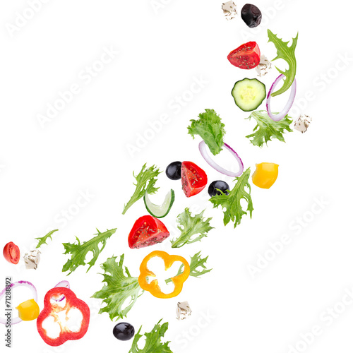 Fresh salad with flying vegetables ingredients isolated on a whi