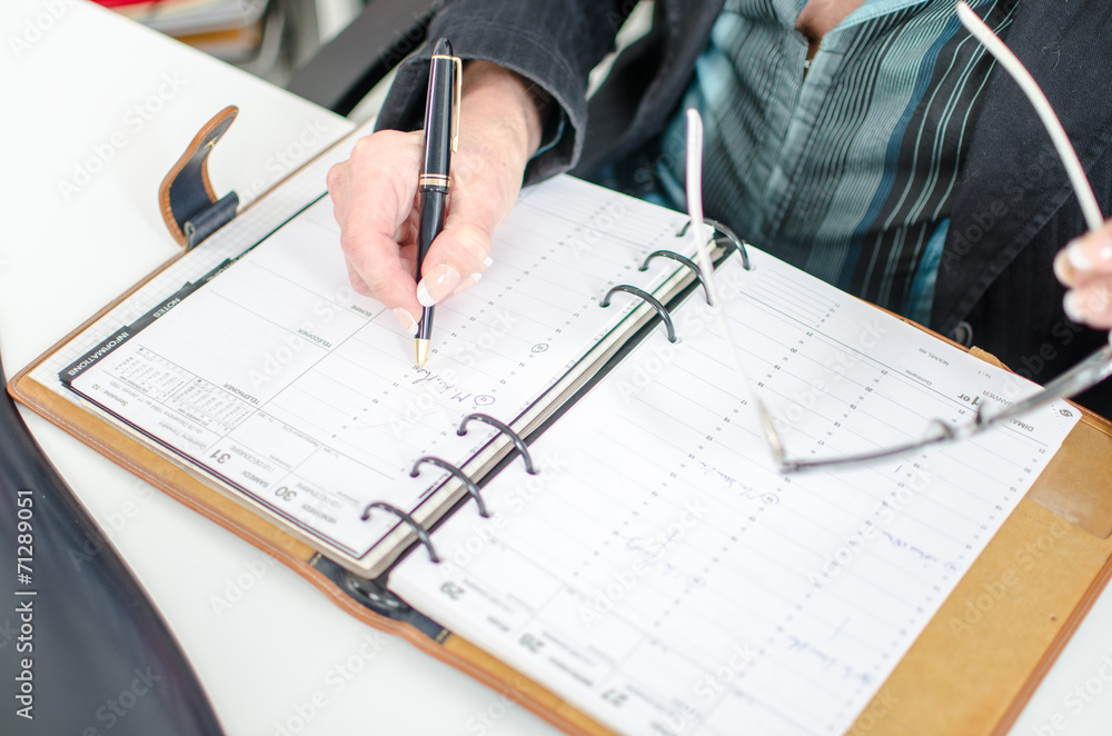 Businesswoman noting an appointment in her diary Businesswoman noting an appointment in her diary