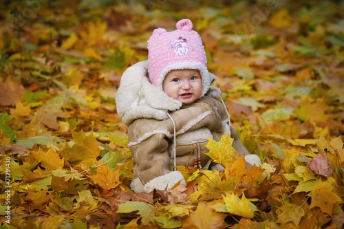 The child sits in the yellow foliage