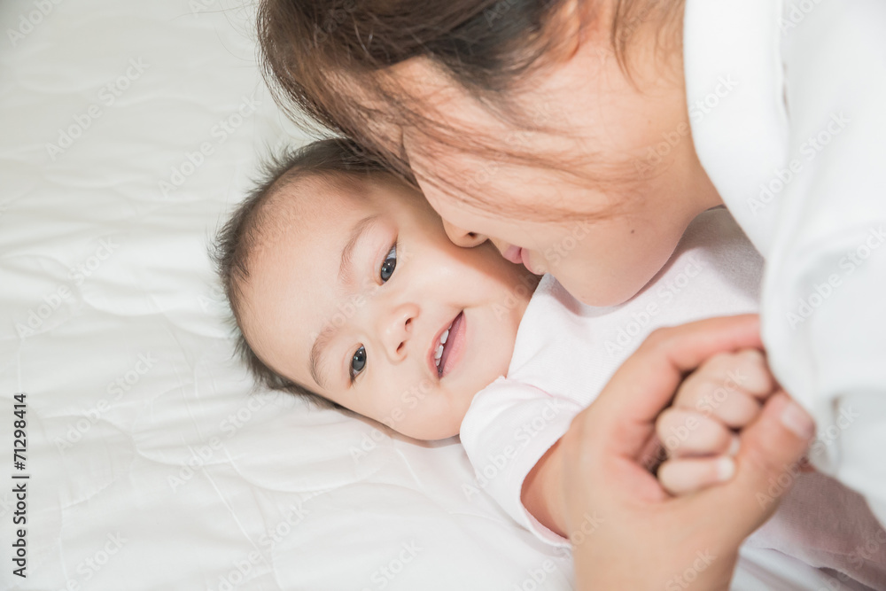Happy cheerful family. Asian mother and baby kissing, laughing a Happy cheerful family. Asian mother and baby kissing, laughing a
