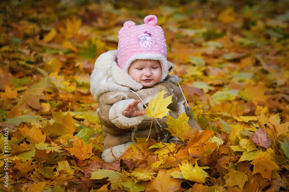 The child sits in the yellow foliage The child sits in the yellow foliage