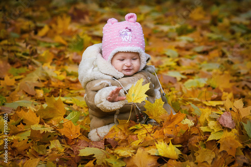 The child sits in the yellow foliage