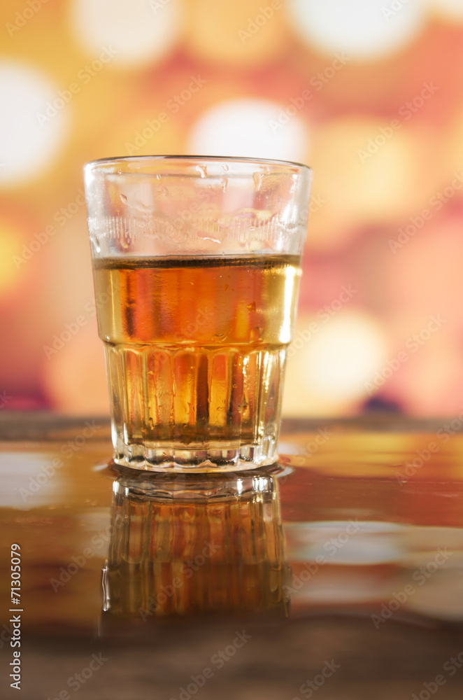 glass of rum whiskey over defocused lights background glass of rum whiskey over defocused lights background