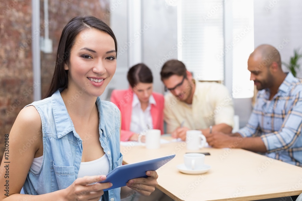 Smiling woman holding tablet in front of her colleague Smiling woman holding tablet in front of her colleague