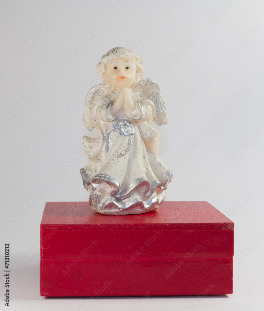 Ceramic sculpture of little angel on a red stand
