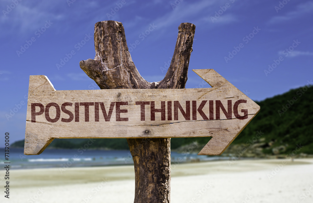 Positive Thinking wooden sign with a beach on background