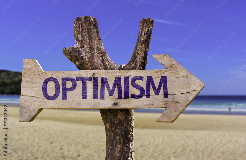 Optimism wooden sign with a beach on background