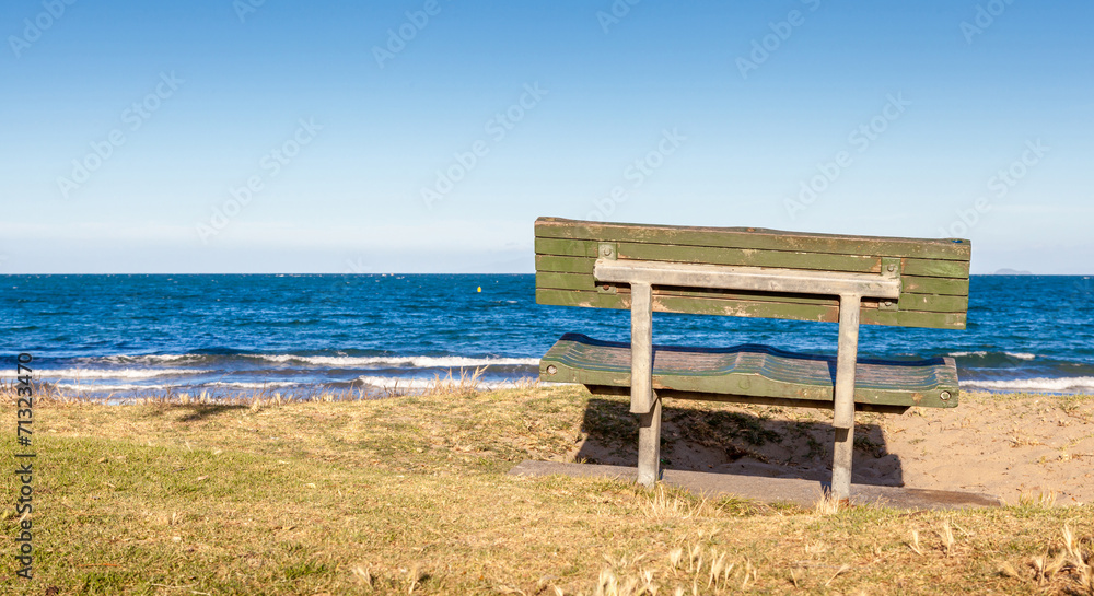 The beautiful view of bench on grass looking out toward the ocea The beautiful view of bench on grass looking out toward the ocea