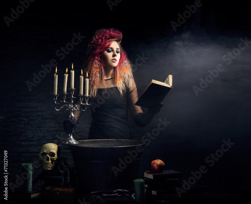 Beautiful witch making witchcraft on a Halloween background