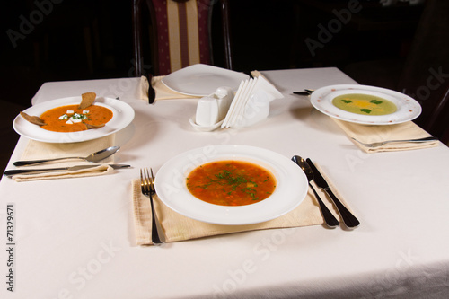 Table set with three different bowls of soup