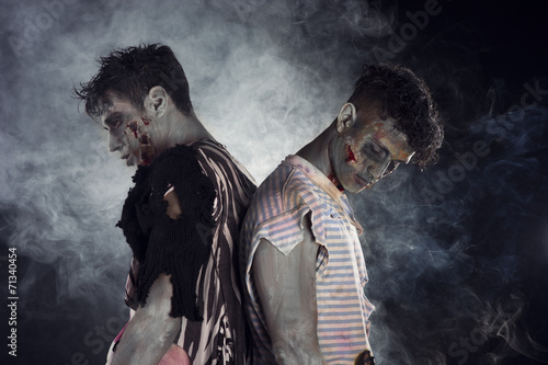 Two male zombies back to back on black smoky background