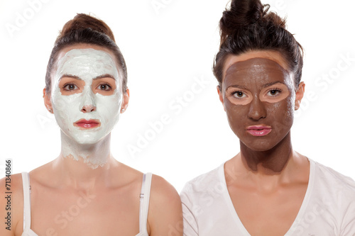 two serious young women with masks posing on white