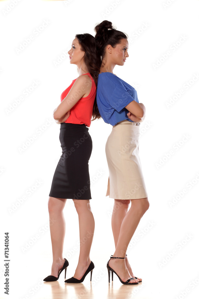 Two angry women leans backs on each other Two angry women leans backs on each other