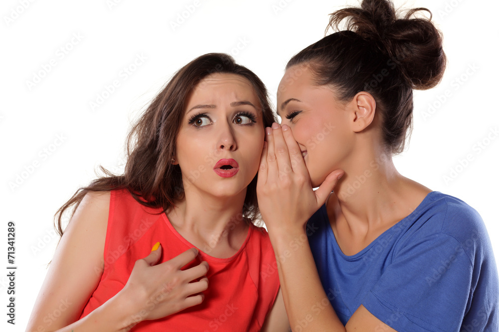 young woman whispers to her mate bad news young woman whispers to her mate bad news