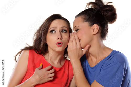 young woman whispers to her mate bad news