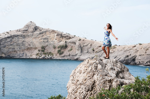 Young woman with backpack standing on cliff's edge