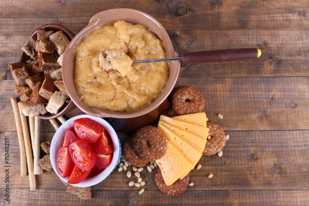 Fondue, slices of cheese, tomatoes and biscuits