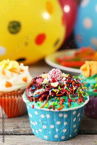 Delicious birthday cupcakes on table on bright background