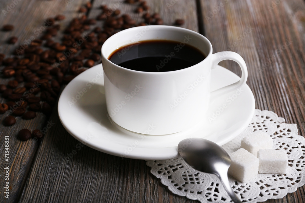 Cup of coffee and coffee beans on napkin on wooden background Cup of coffee and coffee beans on napkin on wooden background
