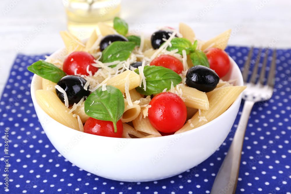 Pasta with tomatoes, olives and basil leaves in bowl