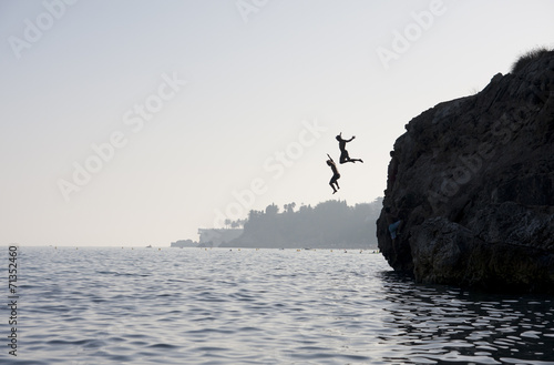 People jumping into the water from cliff