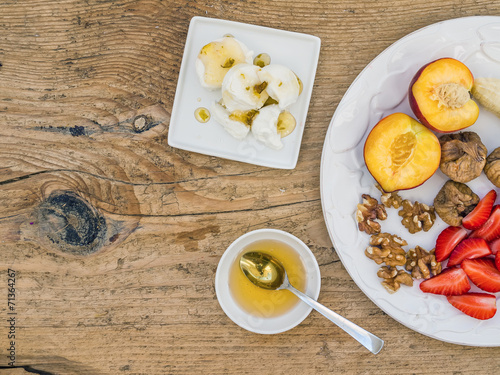 Breakfast set with fresh strawberry, banana, peach, dry figs, wa