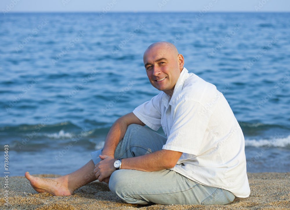  man sitting on   beach near  sea.