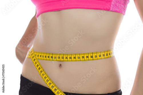 Fit woman measuring her waistline with a tape
