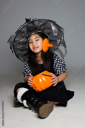 Portrait of little Asian girl in black hat and black clothing with pumskin photo