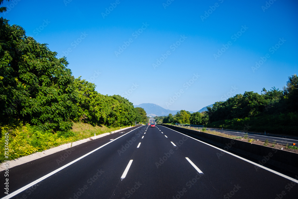 asphalt road through the green field and clouds on blue sky in s asphalt road through the green field and clouds on blue sky in s