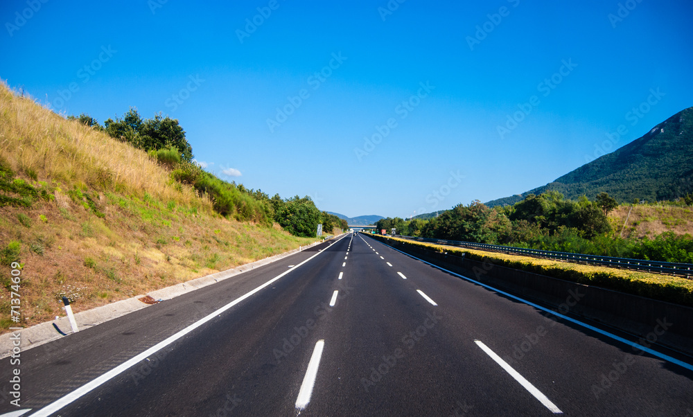 asphalt road through the green field and clouds on blue sky in s asphalt road through the green field and clouds on blue sky in s