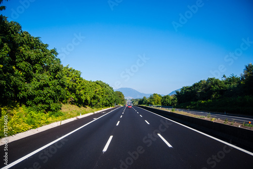 asphalt road through the green field and clouds on blue sky in s
