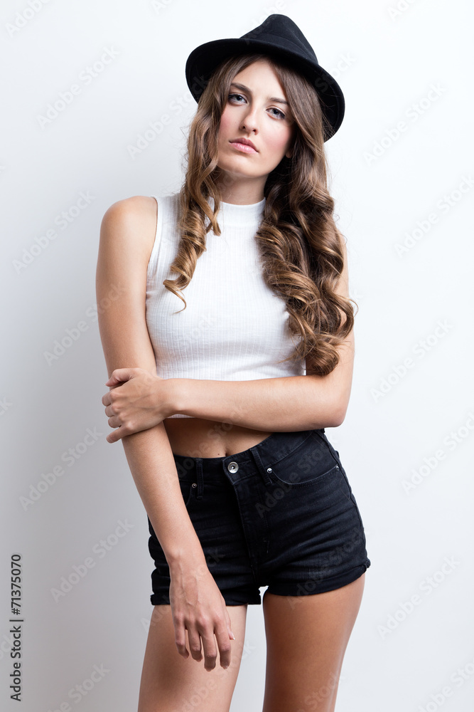 Fashionable brunette woman with long slim legs posing in studio. Fashionable brunette woman with long slim legs posing in studio.