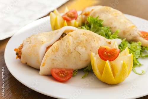 Squids stuffed with seafood on white plate in restaurant