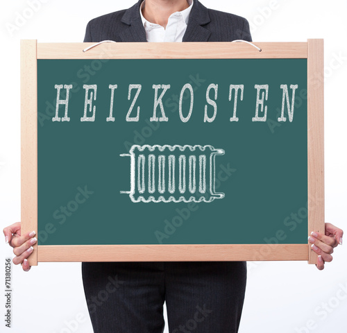 Frau hält Tafel mit dem Wort Heizkosten und dem Symbol Heizung