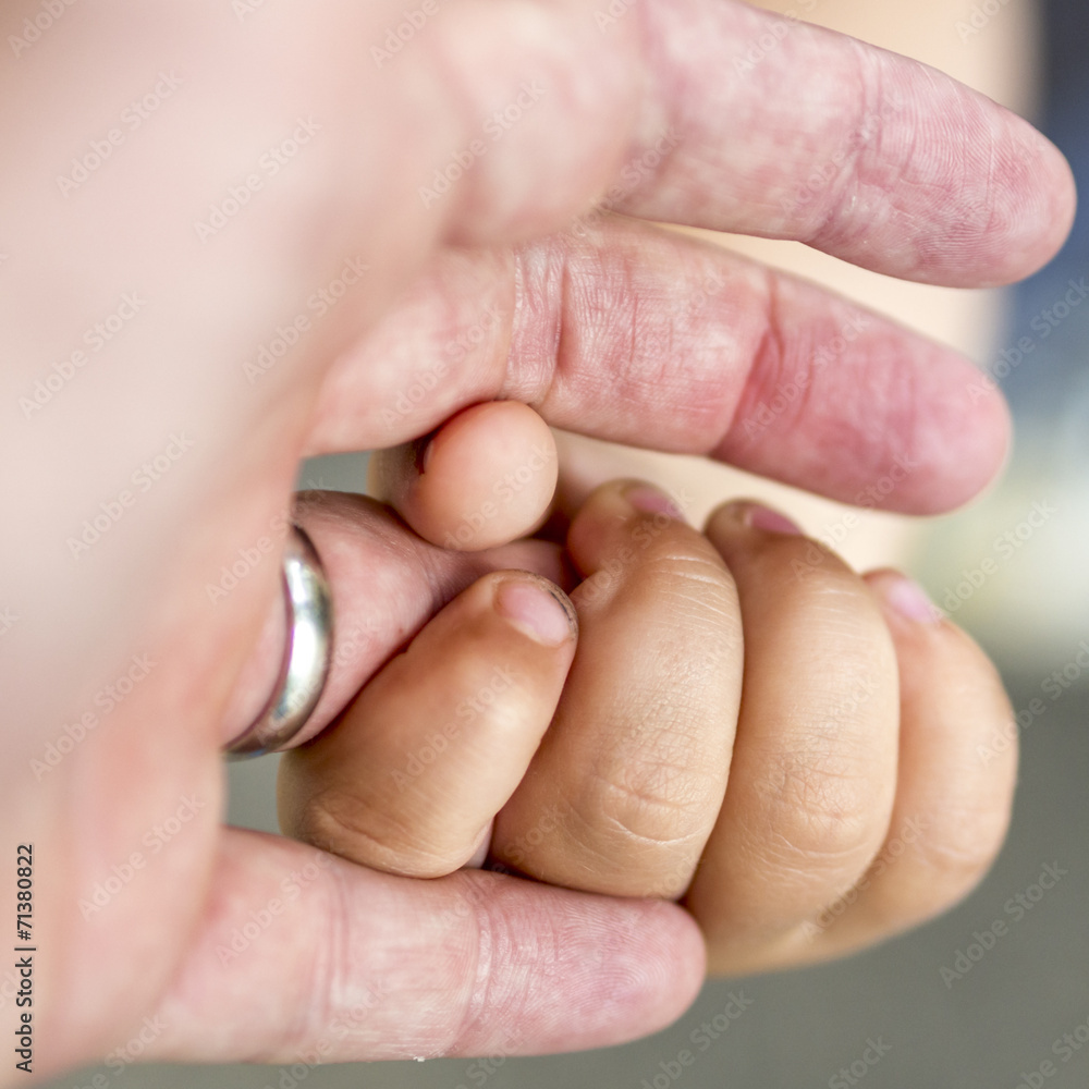 child is holding a ringfinger of his father